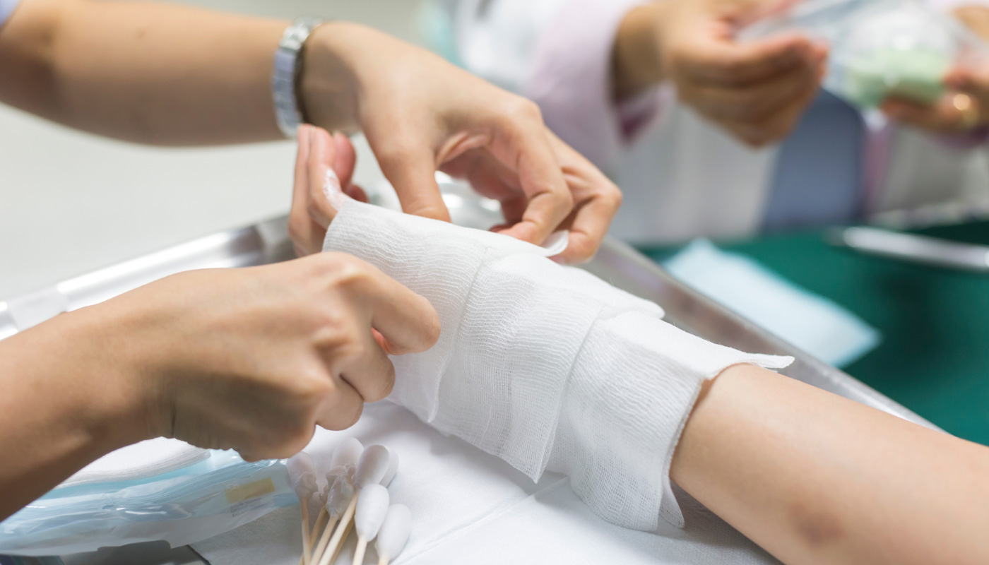 Image shows a person getting a wound dressing on their arm from a burn injury